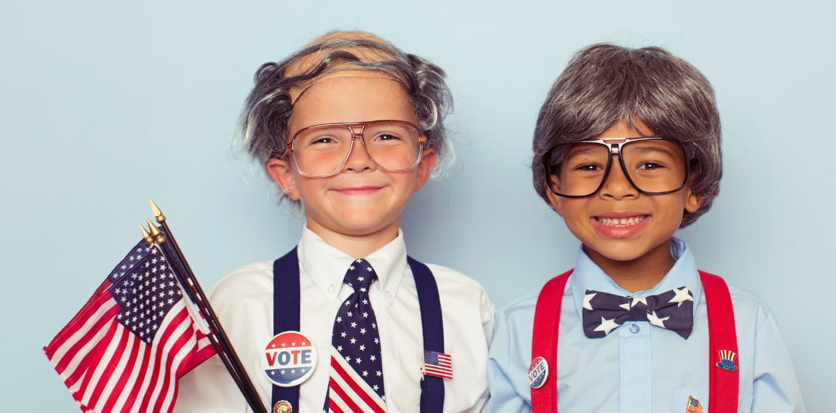 Two children holding flags and signs encouraging others to vote
