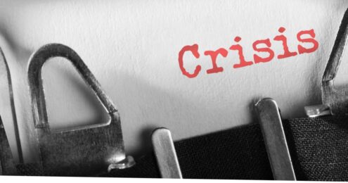 a close up shot of a type writer and piece of paper that says "Crisis" in orange. This represents a government shutdown.