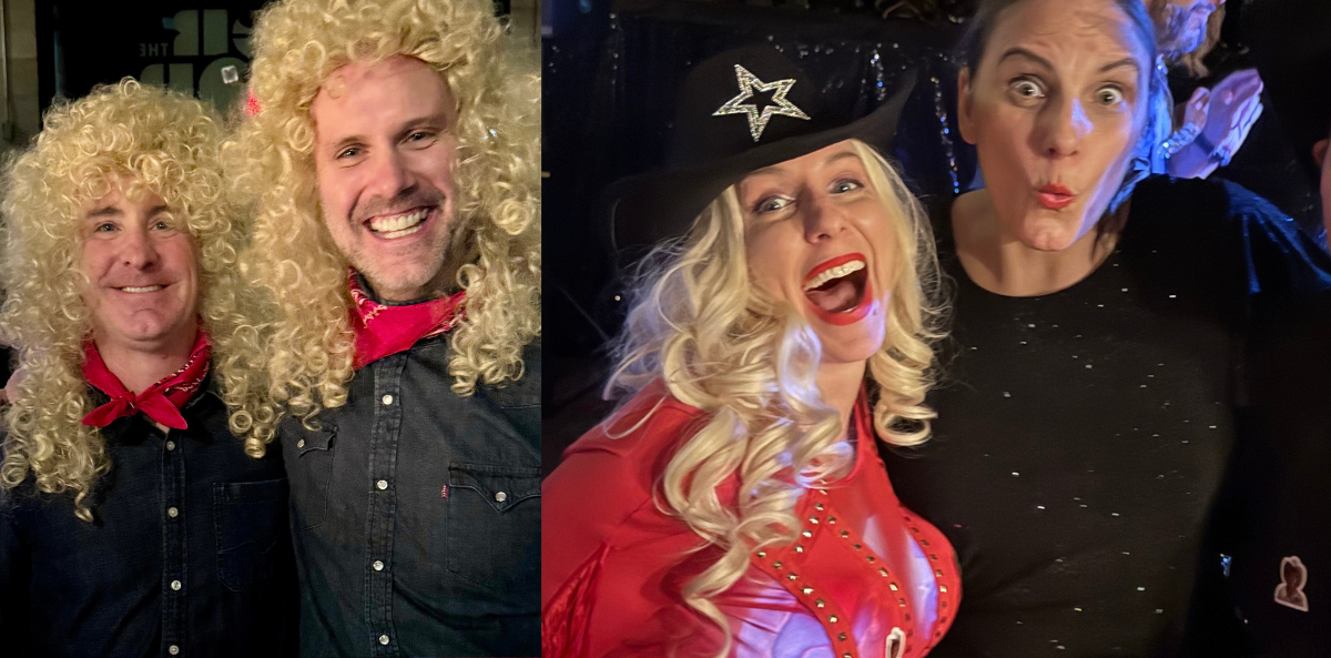 Glennda Testone has fun at a party with friends. A lively photo of four people at what appears to be a costume event. On the left, two men are dressed in Dolly Parton-inspired outfits, wearing curly blonde wigs, red bandanas, and denim shirts, smiling at the camera. On the right, a woman in the center wears a red rhinestone cowgirl outfit, long blonde curls, and a black cowboy hat with a silver star—also channeling Dolly Parton. Standing next to her on the far right is Glennda, wearing a black top with subtle sparkles, pulling a wide-eyed, playful expression. She is the only one not in costume.