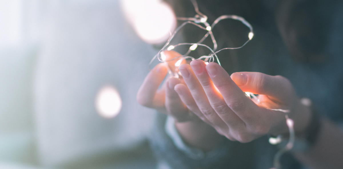 Picture of hands open and turned upright holding wisps of light. Represents the concept of givers.